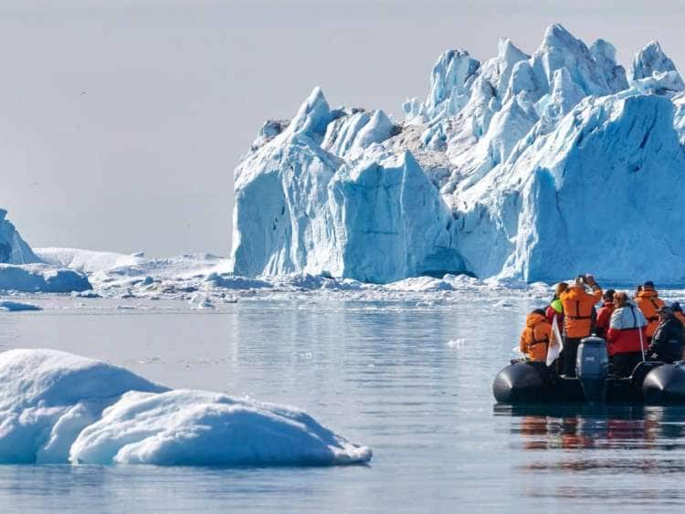 A Zodiac boat with passengers explore among icebergs in Ilulissat, Greenland, a port visited on an all-inclusive, luxury, expedition Seabourn cruise.