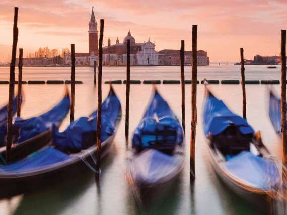Blue gondolas in a row with St. Marks Basilica in background in Venice, Italy, a Mediterranean port to experience on an all-inclusive, luxury Seabourn cruise.