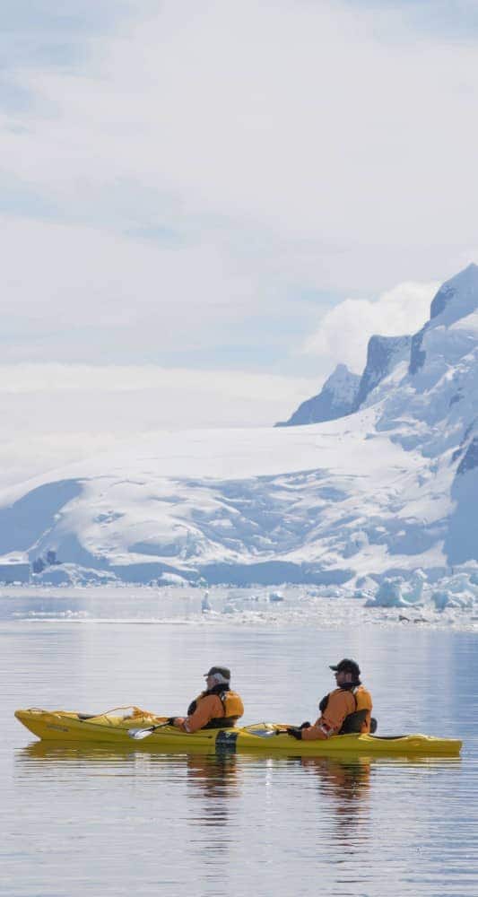 Gäste fahren während einer Antarktis- und Südamerika-Kreuzfahrt mit Seabourn in antarktischen Gewässern Kajak.