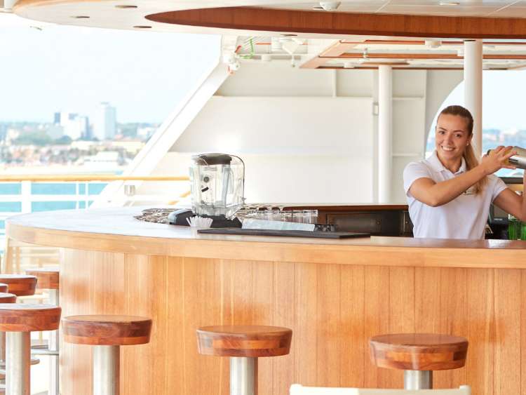 Smiling bartender using shaker behind the Sky Bar aboard an all-inclusive, luxury Seabourn cruise.