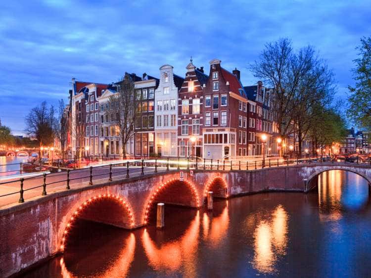 Netherlands, North Holland, Benelux, Amsterdam, Typical Dutch houses and bridge on Keizersgracht and Leidesegracht Canals illuminated at dusk