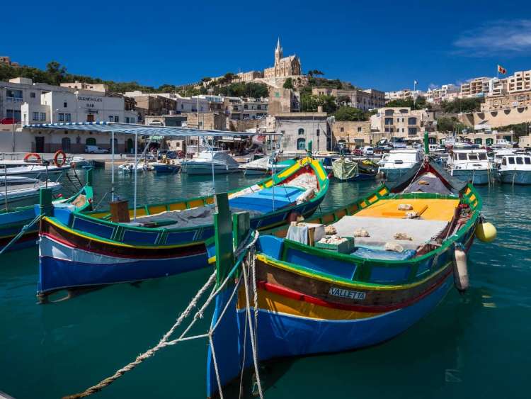 Colorful fishing boats in the harbor of Mgarr on the Island of Gozo, Malta, a port visited on an all-inclusive, luxury Seabourn cruise.