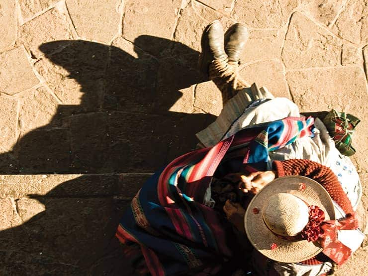 Peruvian man on street with a long shadow. Take a shore excursion to a port in Peru on a Seabourn Antarctica & South America voyage.