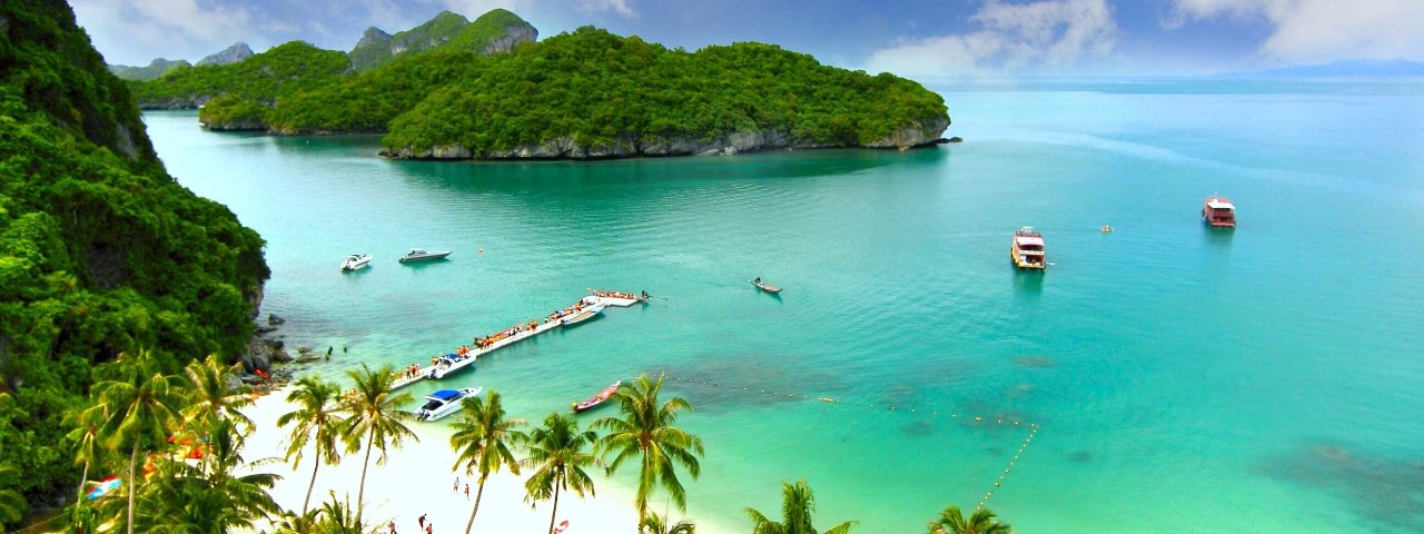 Idyllic beach with aquamarine waters surrounded by lush trees in Ko Samui, Thailand