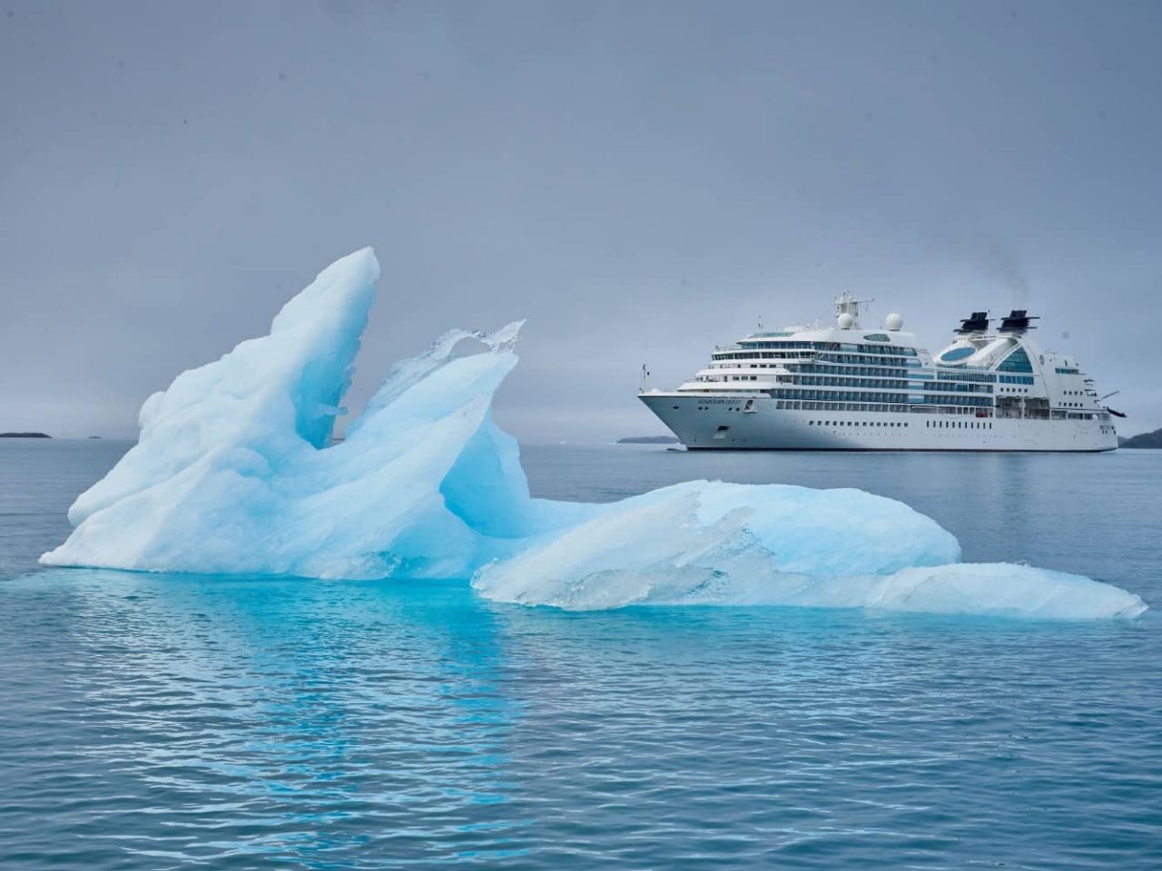 An iceberg floats with a Seabourn ship in background near Arsukfjord, Greenland, an area visited on an all-inclusive, luxury expedition Seabourn cruise. 