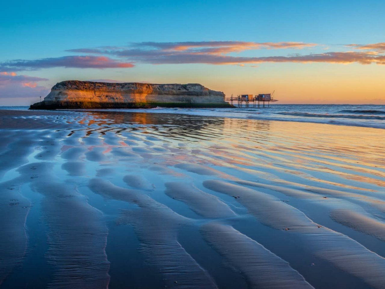 Rock formation at sunset along a rippled beach in the Gironde Estuary, a region visited on an all-inclusive, luxury Seabourn cruise. 