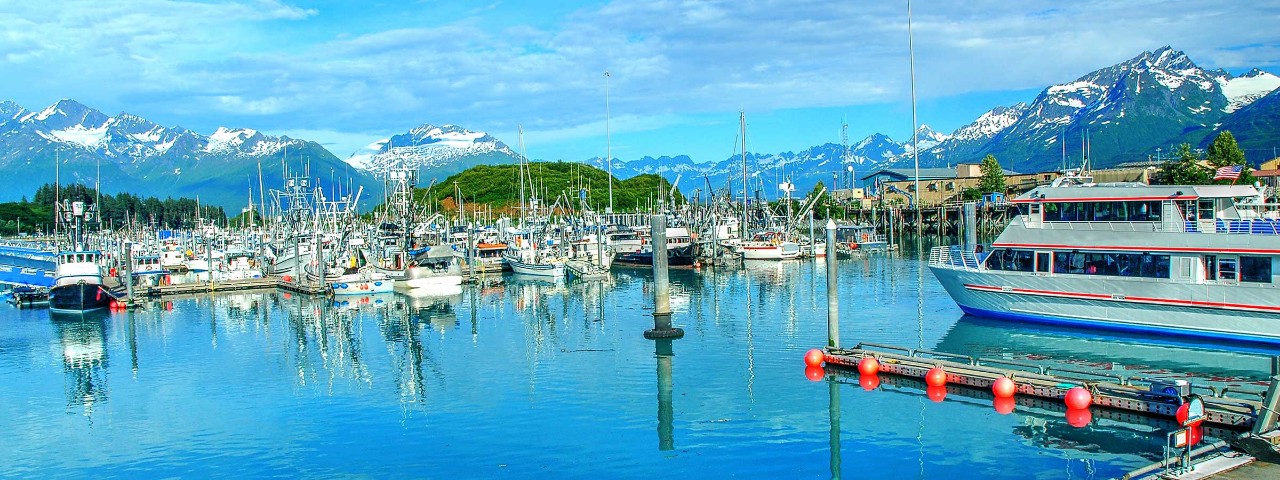 Glacial lake with boats surrounded by snow capped mountains in Valdez, Alaska