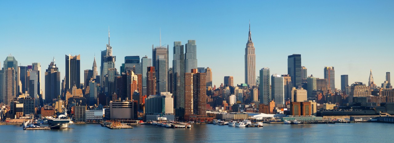 The New York City skyline, seen from across the river, with the Empire State Building prominently featured in the center.