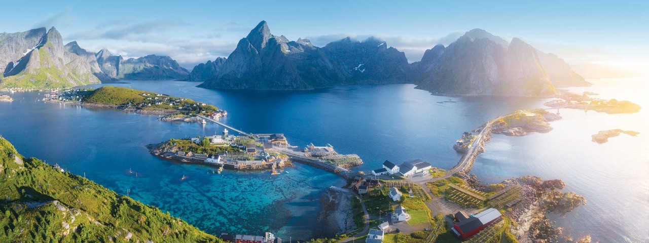 Town surrounded by water with mountain in the background in Reine, Norway