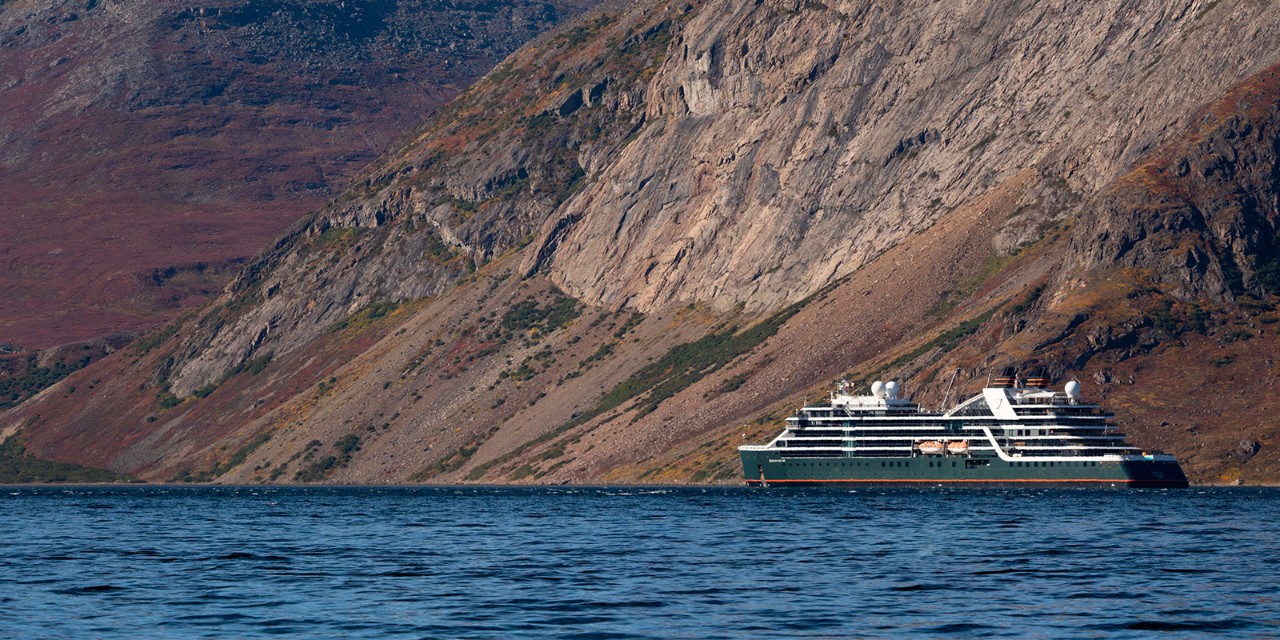 Luxury expedition ship navigating near a rocky shoreline