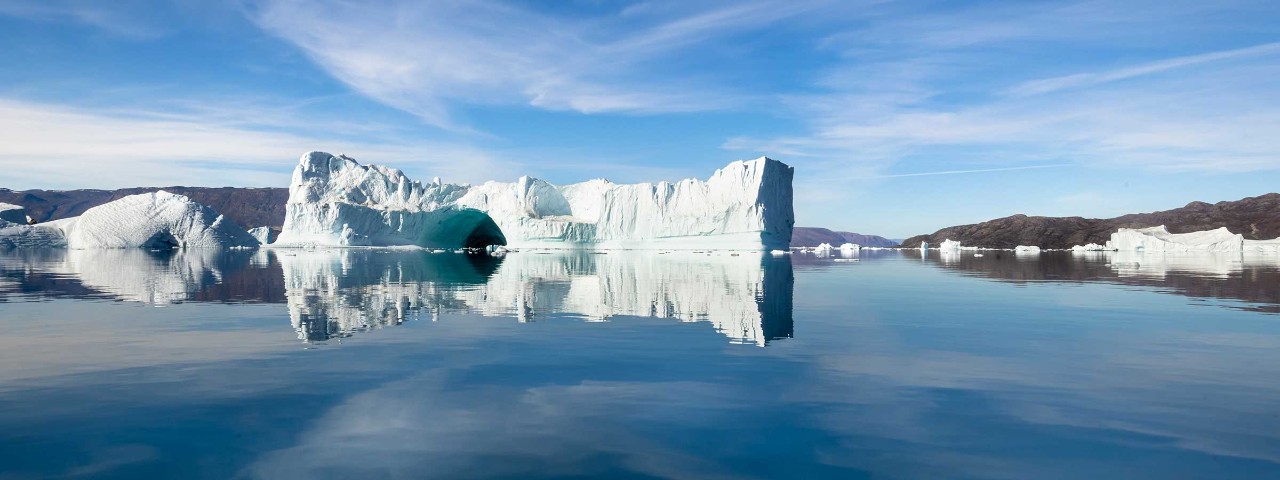White glacier surrounded by water and smaller glaciers in Greenland