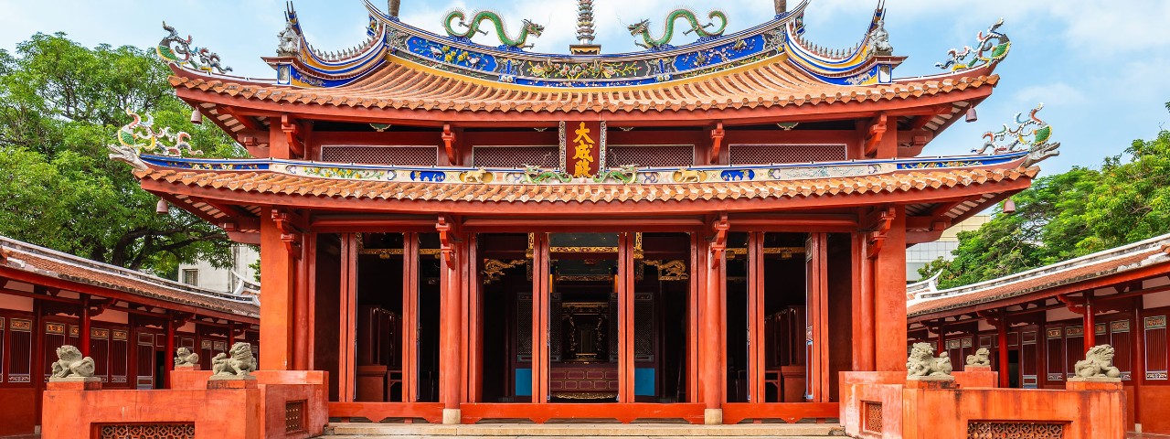 Ornate red Chinese temple in Tainan’s Anping District, with carved columns, dragon-tiled roof, and stone lions, visited on a Seabourn shore excursion.