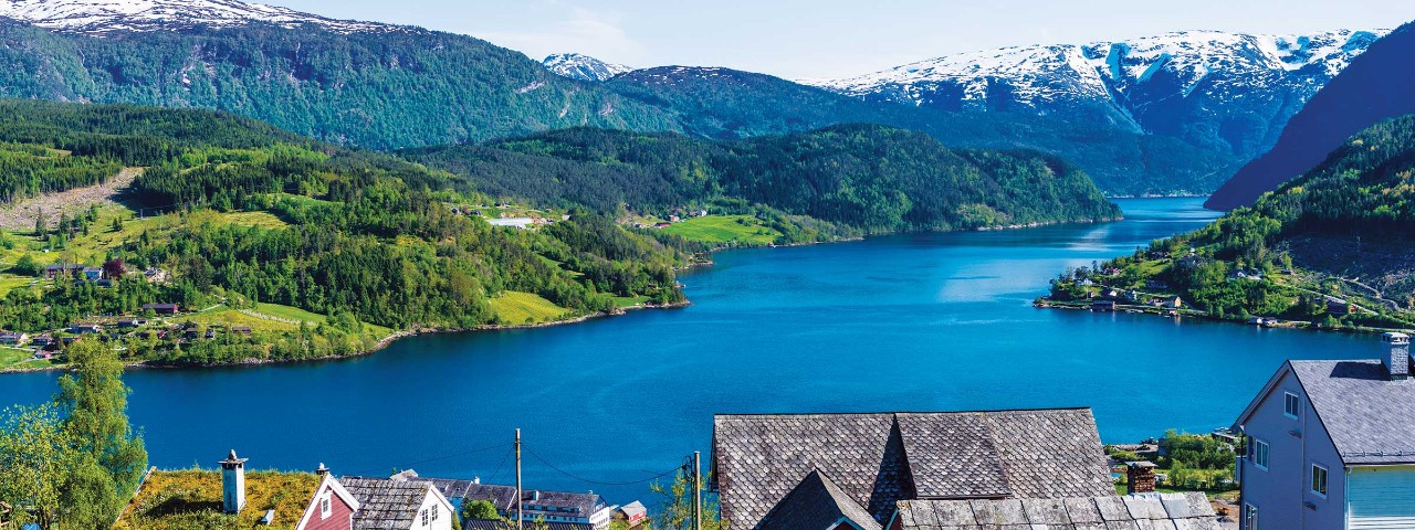 Town surrounded by alpine lake and snow capped mountains